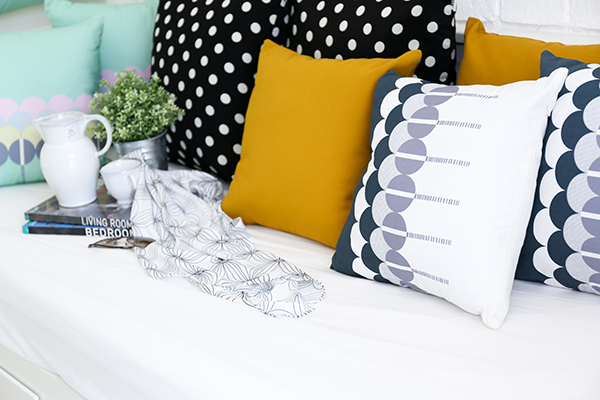 Colorful pillows on a sofa with white brick wall in background