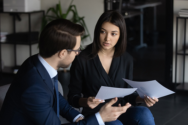 Diverse businesspeople talk brainstorm discuss corporate financial paperwork in office together, multiracial colleagues speak cooperate consider company documents at meeting, collaboration concept