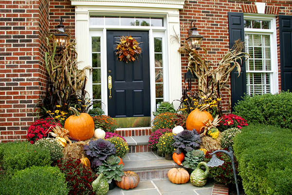 Front door with pumpkins, and other shrubbery around it.